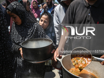 Displaced Palestinians are receiving cooked food rations at a donation point in Deir al-Balah in the central Gaza Strip, on April 16, 2024,...