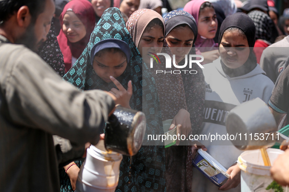 Displaced Palestinians are receiving cooked food rations at a donation point in Deir al-Balah in the central Gaza Strip, on April 16, 2024,...