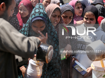 Displaced Palestinians are receiving cooked food rations at a donation point in Deir al-Balah in the central Gaza Strip, on April 16, 2024,...