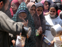 Displaced Palestinians are receiving cooked food rations at a donation point in Deir al-Balah in the central Gaza Strip, on April 16, 2024,...