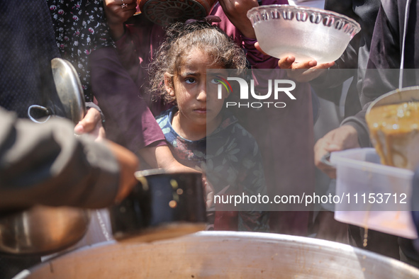 Displaced Palestinians are receiving cooked food rations at a donation point in Deir al-Balah in the central Gaza Strip, on April 16, 2024,...