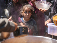 Displaced Palestinians are receiving cooked food rations at a donation point in Deir al-Balah in the central Gaza Strip, on April 16, 2024,...