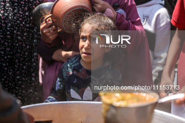 Displaced Palestinians are receiving cooked food rations at a donation point in Deir al-Balah in the central Gaza Strip, on April 16, 2024,...