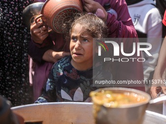 Displaced Palestinians are receiving cooked food rations at a donation point in Deir al-Balah in the central Gaza Strip, on April 16, 2024,...