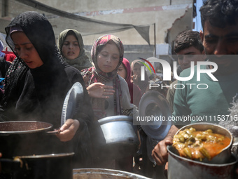 Displaced Palestinians are receiving cooked food rations at a donation point in Deir al-Balah in the central Gaza Strip, on April 16, 2024,...