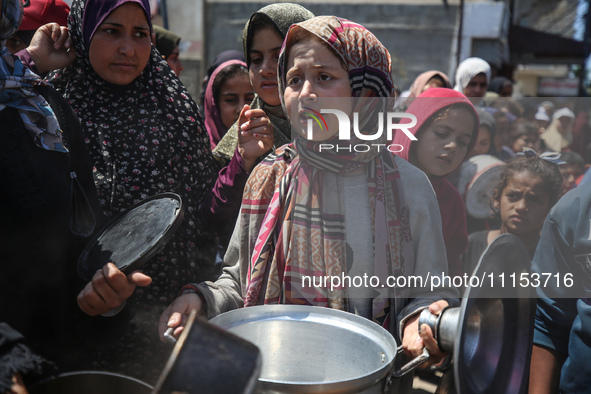 Displaced Palestinians are receiving cooked food rations at a donation point in Deir al-Balah in the central Gaza Strip, on April 16, 2024,...