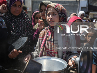 Displaced Palestinians are receiving cooked food rations at a donation point in Deir al-Balah in the central Gaza Strip, on April 16, 2024,...