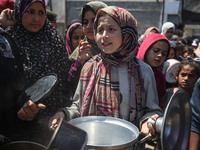 Displaced Palestinians are receiving cooked food rations at a donation point in Deir al-Balah in the central Gaza Strip, on April 16, 2024,...