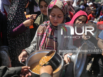 Displaced Palestinians are receiving cooked food rations at a donation point in Deir al-Balah in the central Gaza Strip, on April 16, 2024,...