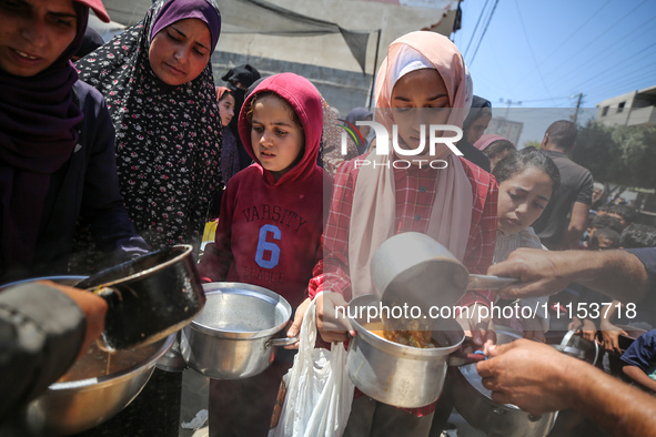 Displaced Palestinians are receiving cooked food rations at a donation point in Deir al-Balah in the central Gaza Strip, on April 16, 2024,...