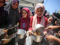 Displaced Palestinians are receiving cooked food rations at a donation point in Deir al-Balah in the central Gaza Strip, on April 16, 2024,...