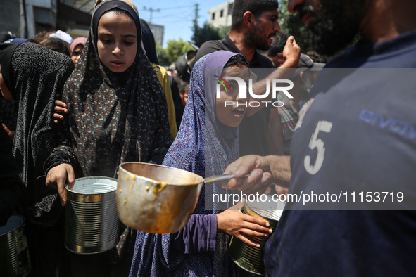 Displaced Palestinians are receiving cooked food rations at a donation point in Deir al-Balah in the central Gaza Strip, on April 16, 2024,...