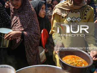 Displaced Palestinians are receiving cooked food rations at a donation point in Deir al-Balah in the central Gaza Strip, on April 16, 2024,...