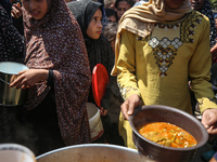 Displaced Palestinians are receiving cooked food rations at a donation point in Deir al-Balah in the central Gaza Strip, on April 16, 2024,...