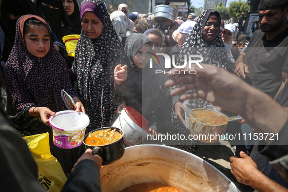 Displaced Palestinians are receiving cooked food rations at a donation point in Deir al-Balah in the central Gaza Strip, on April 16, 2024,...