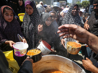 Displaced Palestinians are receiving cooked food rations at a donation point in Deir al-Balah in the central Gaza Strip, on April 16, 2024,...