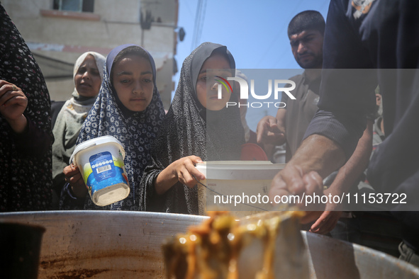 Displaced Palestinians are receiving cooked food rations at a donation point in Deir al-Balah in the central Gaza Strip, on April 16, 2024,...