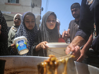 Displaced Palestinians are receiving cooked food rations at a donation point in Deir al-Balah in the central Gaza Strip, on April 16, 2024,...