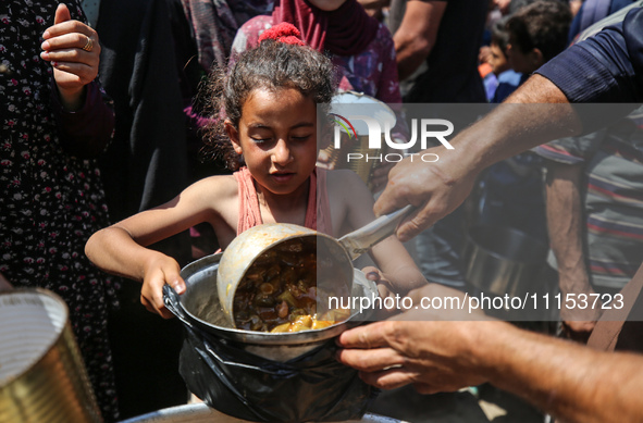 Displaced Palestinians are receiving cooked food rations at a donation point in Deir al-Balah in the central Gaza Strip, on April 16, 2024,...