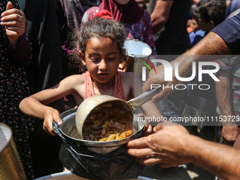 Displaced Palestinians are receiving cooked food rations at a donation point in Deir al-Balah in the central Gaza Strip, on April 16, 2024,...