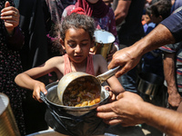 Displaced Palestinians are receiving cooked food rations at a donation point in Deir al-Balah in the central Gaza Strip, on April 16, 2024,...