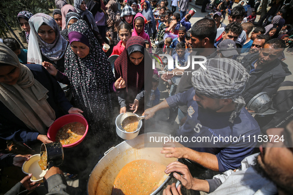 Displaced Palestinians are receiving cooked food rations at a donation point in Deir al-Balah in the central Gaza Strip, on April 16, 2024,...