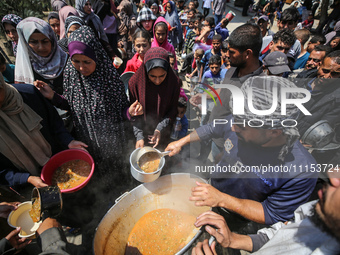 Displaced Palestinians are receiving cooked food rations at a donation point in Deir al-Balah in the central Gaza Strip, on April 16, 2024,...