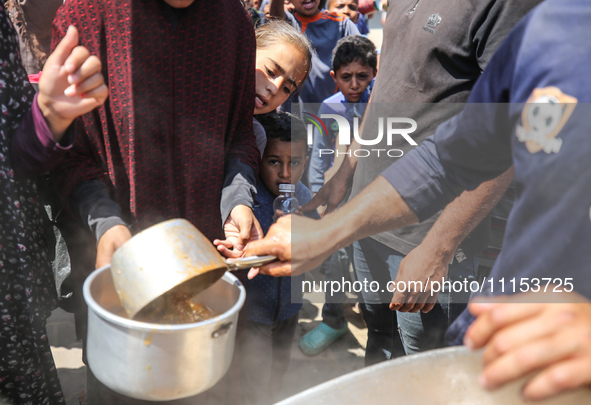 Displaced Palestinians are receiving cooked food rations at a donation point in Deir al-Balah in the central Gaza Strip, on April 16, 2024,...