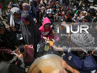 Displaced Palestinians are receiving cooked food rations at a donation point in Deir al-Balah in the central Gaza Strip, on April 16, 2024,...