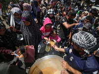 Displaced Palestinians are receiving cooked food rations at a donation point in Deir al-Balah in the central Gaza Strip, on April 16, 2024,...