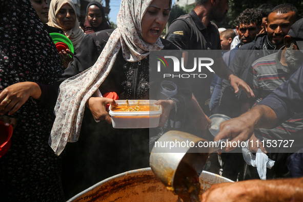 Displaced Palestinians are receiving cooked food rations at a donation point in Deir al-Balah in the central Gaza Strip, on April 16, 2024,...