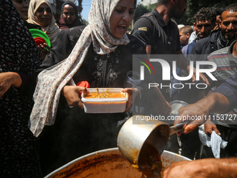 Displaced Palestinians are receiving cooked food rations at a donation point in Deir al-Balah in the central Gaza Strip, on April 16, 2024,...