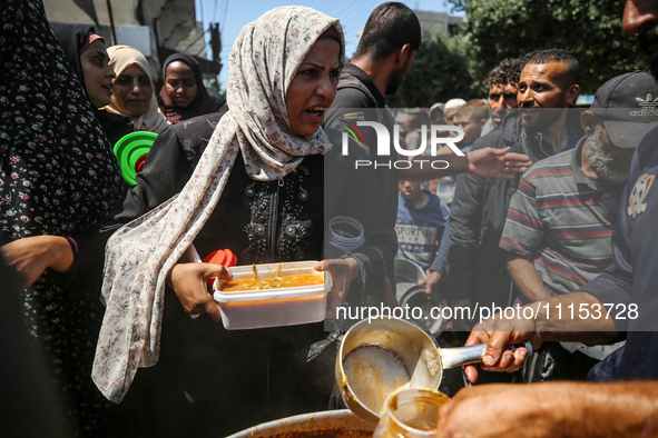 Displaced Palestinians are receiving cooked food rations at a donation point in Deir al-Balah in the central Gaza Strip, on April 16, 2024,...