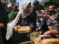 Displaced Palestinians are receiving cooked food rations at a donation point in Deir al-Balah in the central Gaza Strip, on April 16, 2024,...