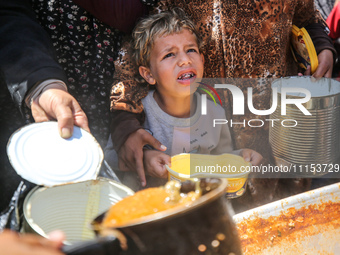 Displaced Palestinians are receiving cooked food rations at a donation point in Deir al-Balah in the central Gaza Strip, on April 16, 2024,...