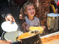 Displaced Palestinians are receiving cooked food rations at a donation point in Deir al-Balah in the central Gaza Strip, on April 16, 2024,...