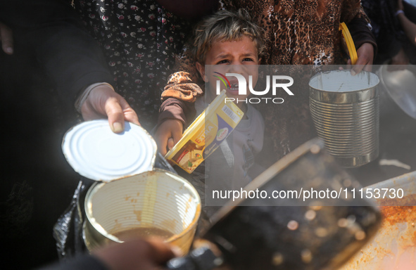 Displaced Palestinians are receiving cooked food rations at a donation point in Deir al-Balah in the central Gaza Strip, on April 16, 2024,...