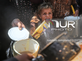 Displaced Palestinians are receiving cooked food rations at a donation point in Deir al-Balah in the central Gaza Strip, on April 16, 2024,...