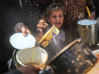 Displaced Palestinians are receiving cooked food rations at a donation point in Deir al-Balah in the central Gaza Strip, on April 16, 2024,...