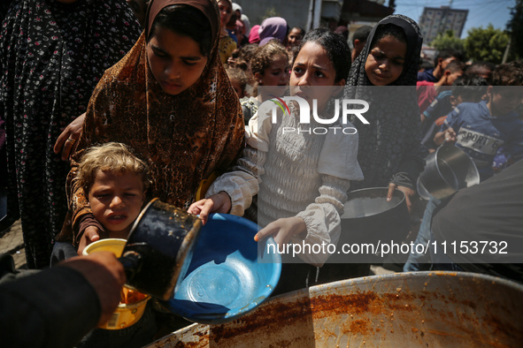 Displaced Palestinians are receiving cooked food rations at a donation point in Deir al-Balah in the central Gaza Strip, on April 16, 2024,...