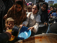 Displaced Palestinians are receiving cooked food rations at a donation point in Deir al-Balah in the central Gaza Strip, on April 16, 2024,...