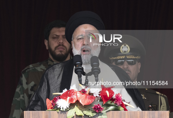 Iranian President Ebrahim Raisi (C) is addressing attendees at a military parade marking Iran's Army Day anniversary at an Army military bas...