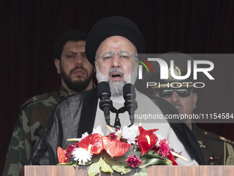 Iranian President Ebrahim Raisi (C) is addressing attendees at a military parade marking Iran's Army Day anniversary at an Army military bas...