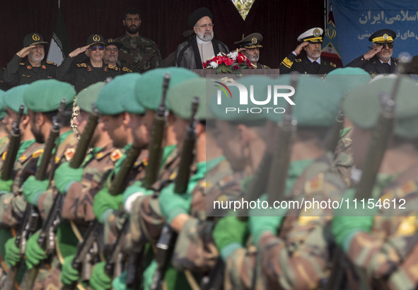 Iranian President Ebrahim Raisi is standing with the Islamic Revolutionary Guard Corps (IRGC) commanders on his left, and Iranian Army comma...