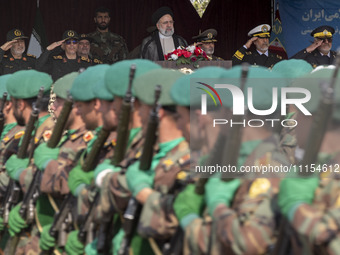 Iranian President Ebrahim Raisi is standing with the Islamic Revolutionary Guard Corps (IRGC) commanders on his left, and Iranian Army comma...