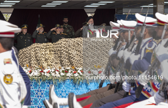 Iranian President Ebrahim Raisi is standing with the Islamic Revolutionary Guard Corps (IRGC) commanders while attending a military parade m...