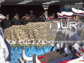 Iranian President Ebrahim Raisi is standing with the Islamic Revolutionary Guard Corps (IRGC) commanders while attending a military parade m...