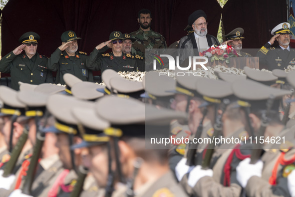 Iranian President Ebrahim Raisi is standing with the Islamic Revolutionary Guard Corps (IRGC) commanders on his left, and Iranian Army comma...