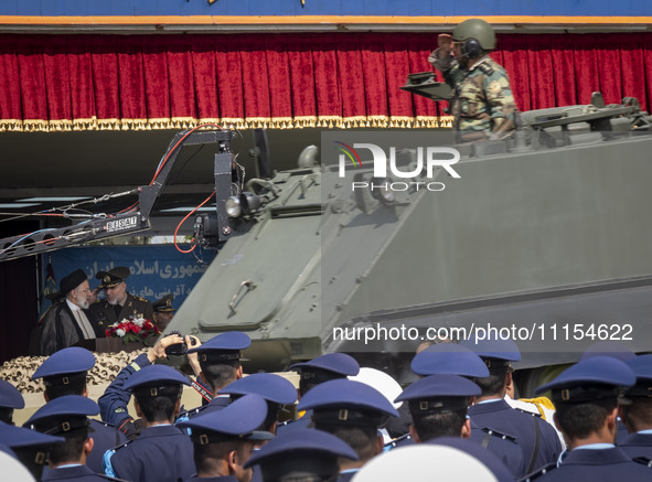 Iranian President Ebrahim Raisi (L) is speaking with an Iranian Army Major General, while a military personnel is saluting and standing on a...