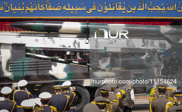 Iranian President Ebrahim Raisi (4th L) is looking at an Iranian missile being carried by a truck while standing with the Islamic Revolution...